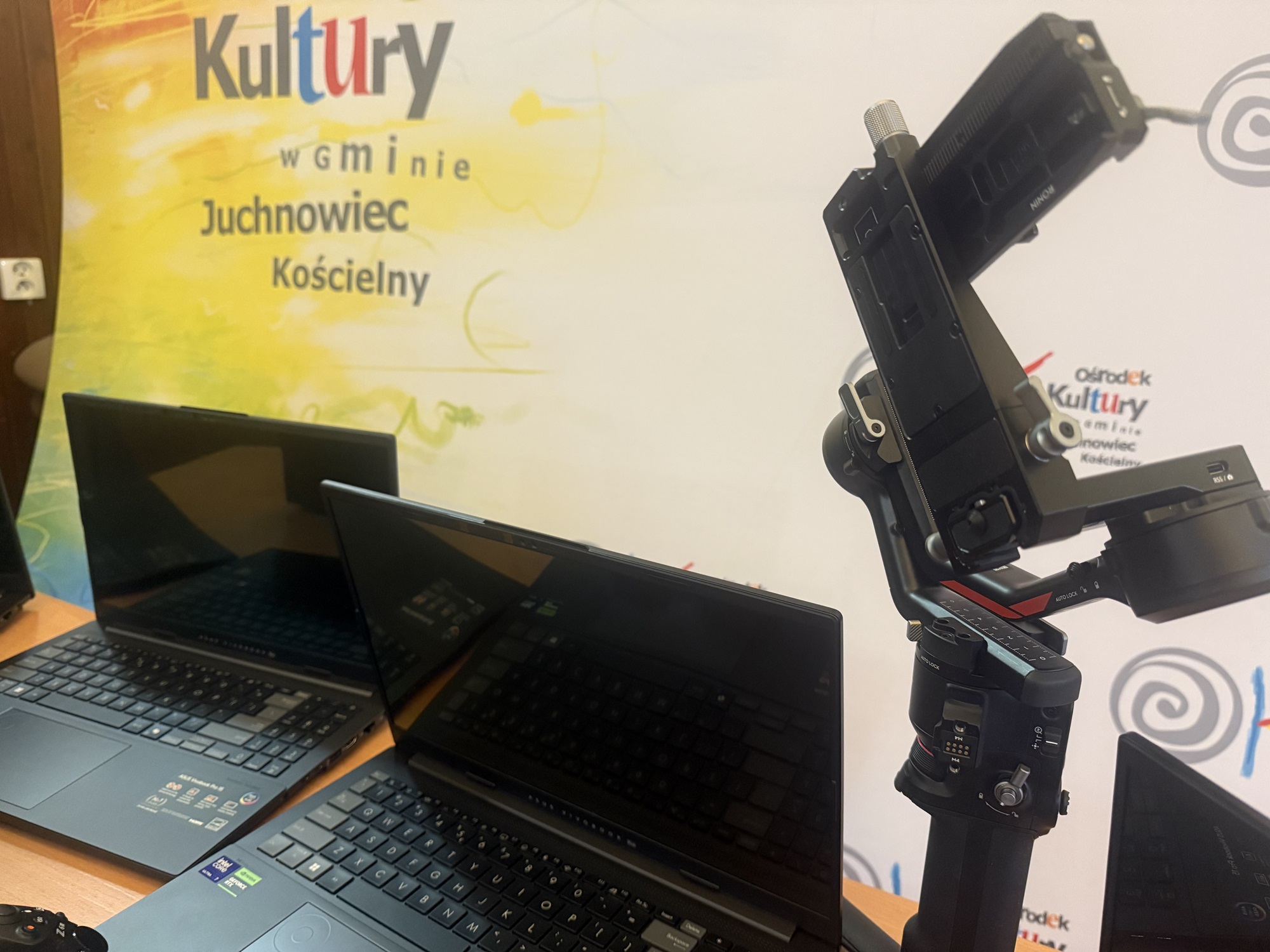 zdjęcie przedstawia sprzęt (laptopy i aparat fotograficzny) zakupione w ramach projektu „Doposażenie Pracowni Edukacji Artystycznej Ośrodka Kultury w Gminie Juchnowiec Kościelny w nowoczesny sprzęt technologiczny wspierający działania artystyczne i edukacyjne”